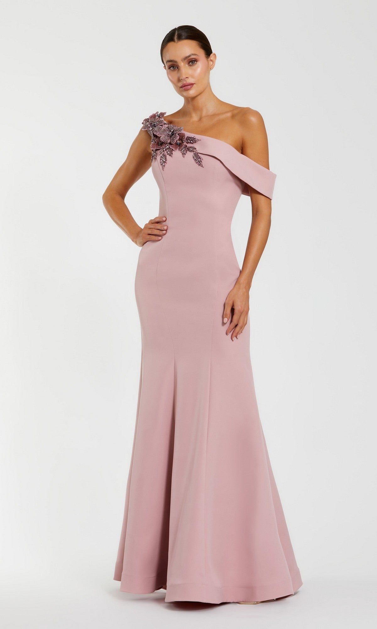 Woman in a rose Mac Duggal 11947 long formal dress with one shoulder and floral bodice embellishments, standing against a plain light background.